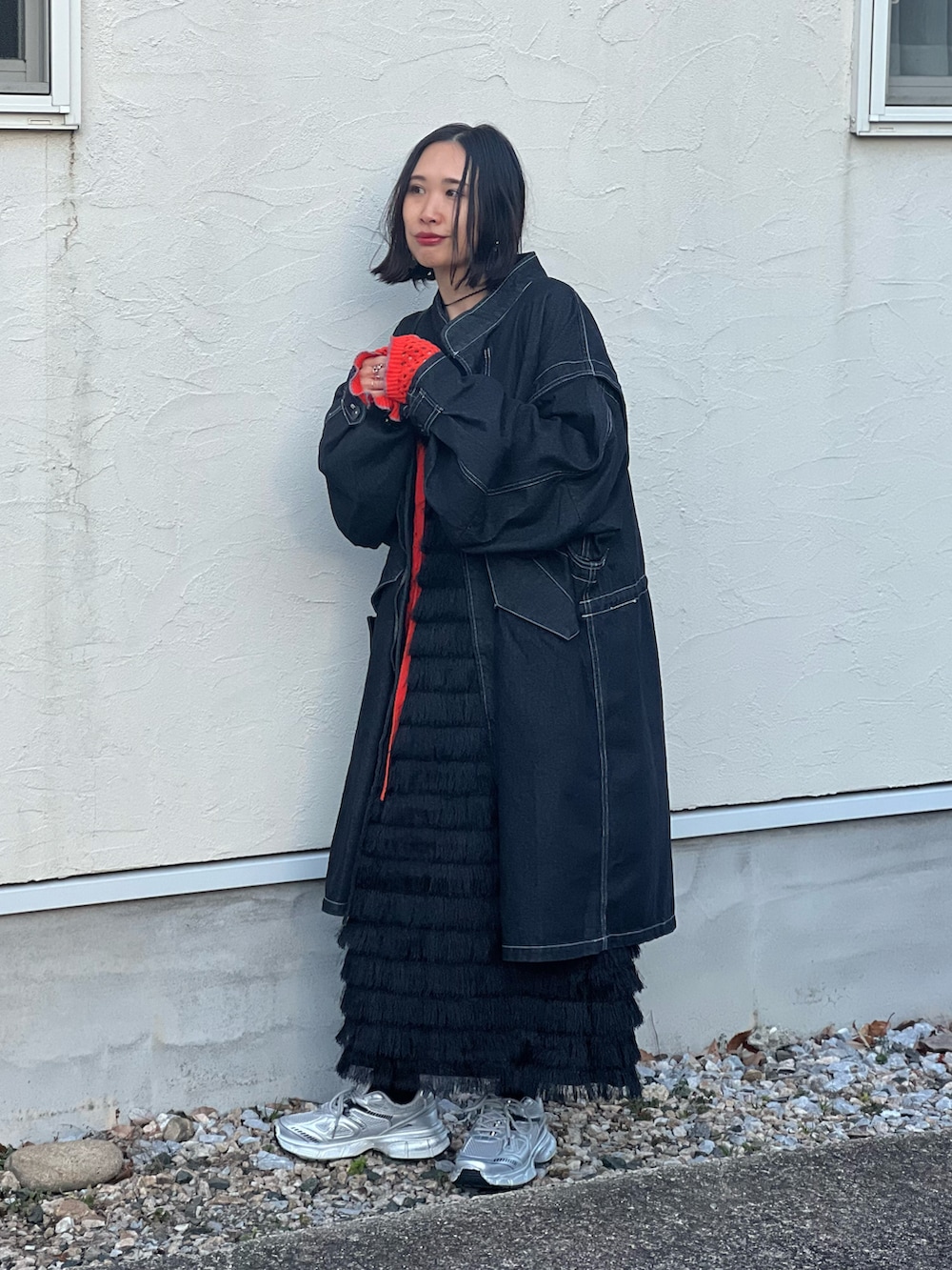 ブラック系のモッズコート、オレンジ系のカーディガン/ボレロ、ブラック系のワンピースを着用したレディースの冬コーディネートの3枚目の写真