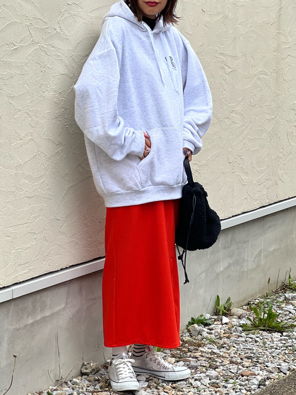 グレー系のパーカー、オレンジ系のスカート、シルバー系のスニーカーを着用したレディースの秋コーディネートの5枚目の写真