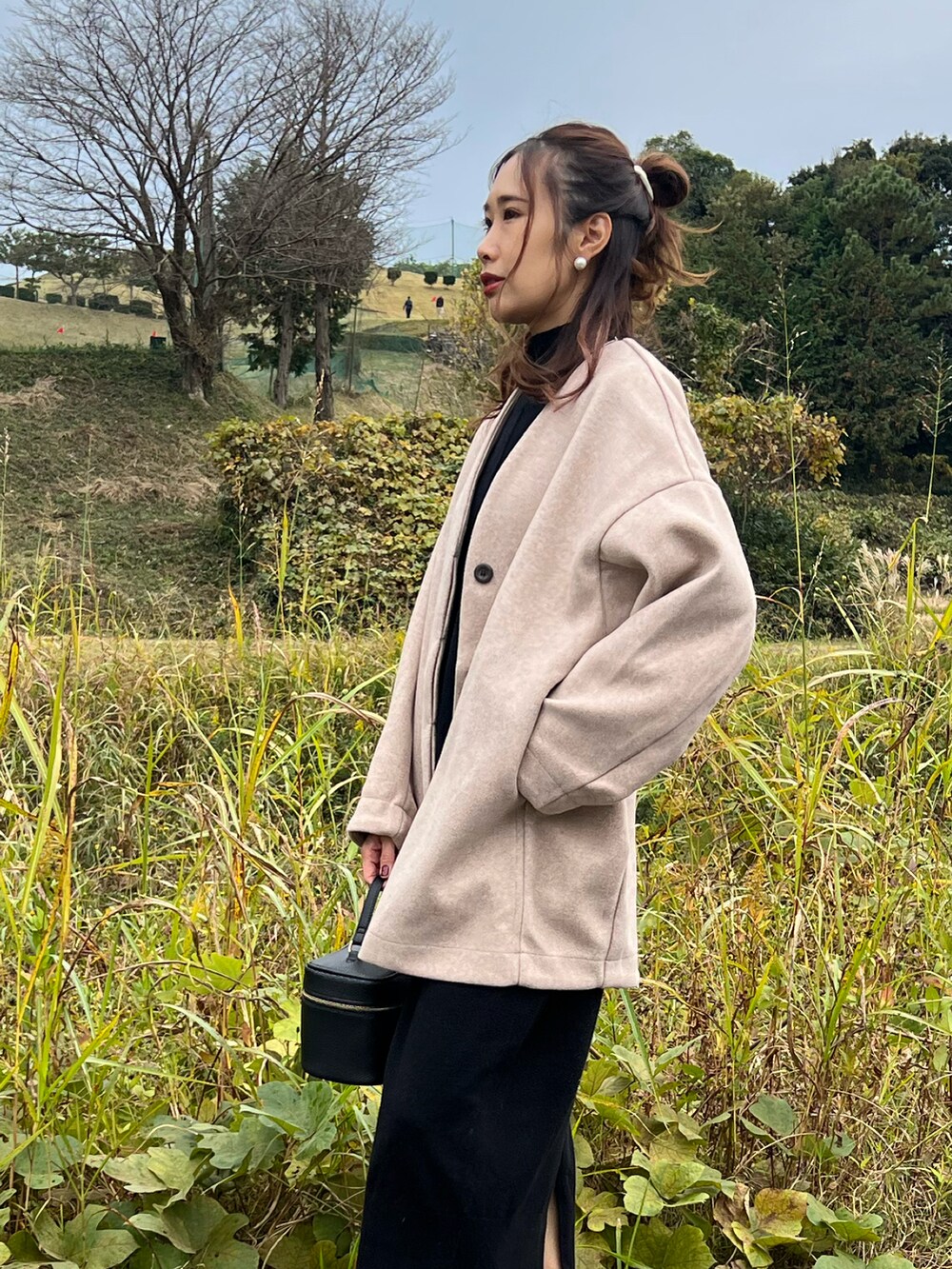 ピンク系のノーカラーコート、ブラック系のワンピース、ブラック系のブーツを着用したレディースの秋コーディネートの4枚目の写真