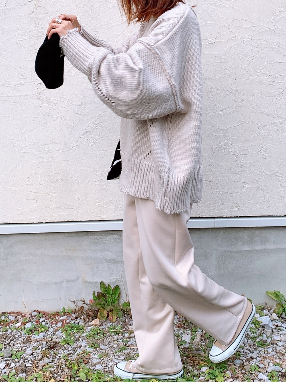 グレー系のニット/セーター、ホワイト系のスラックス、ベージュ系のスニーカーを着用したレディースの秋コーディネートの4枚目の写真