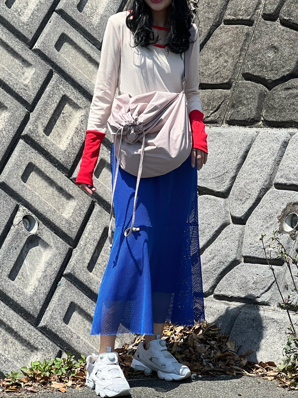 レッド系のTシャツ/カットソー、ブルー系のスカート、グレー系のスニーカーを着用したレディースの春コーディネートの4枚目の写真