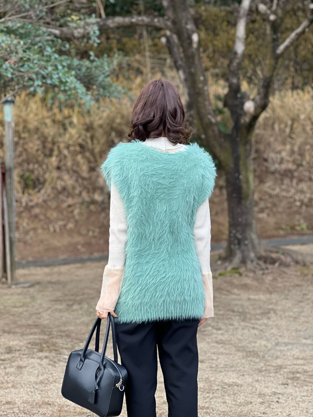 グリーン系のニット/セーター、ベージュ系のニット/セーター、ブラック系のボストンバッグを着用したレディースの冬コーディネートの2枚目の写真