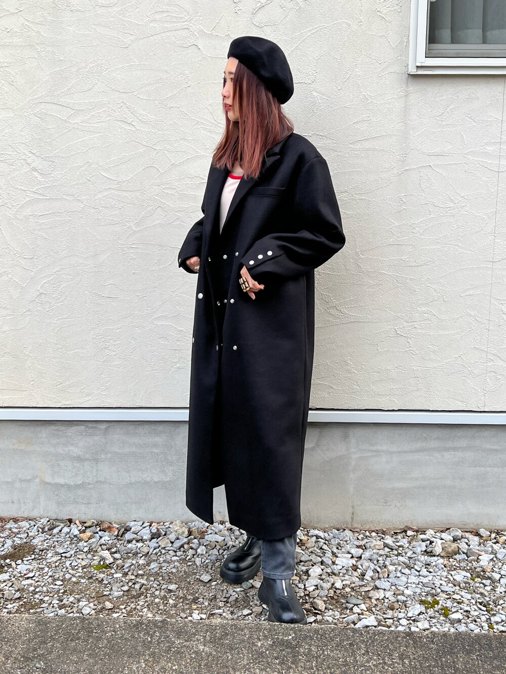 グレー系のデニムパンツ、レッド系のTシャツ/カットソー、ブラック系のチェスターコートを着用したレディースの冬コーディネートの3枚目の写真