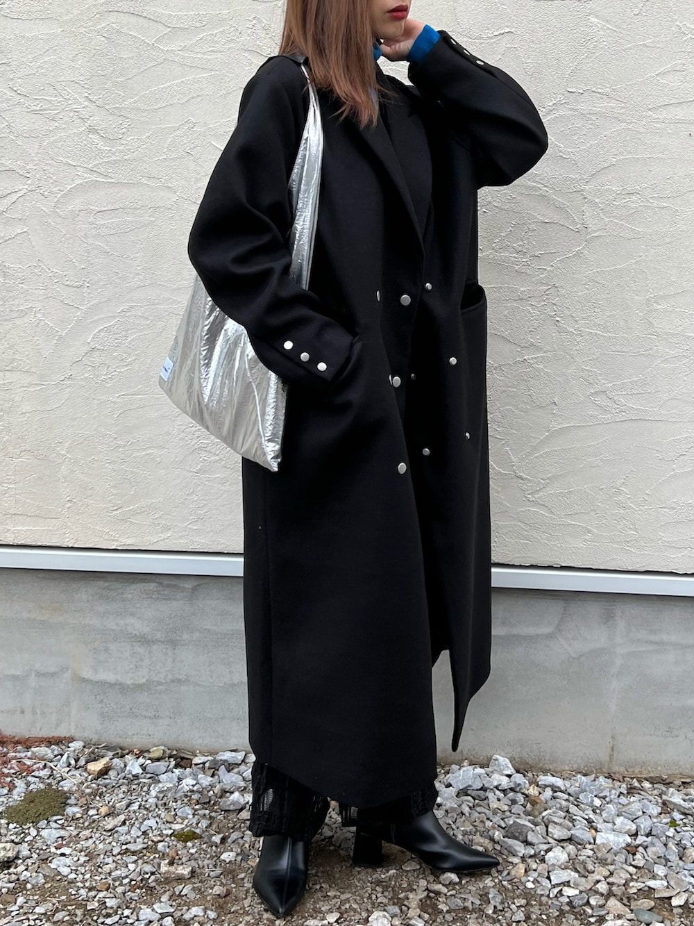 ブラック系のチェスターコート、ブルー系のニット/セーター、ブラック系のその他パンツを着用したレディースの秋コーディネートの3枚目の写真