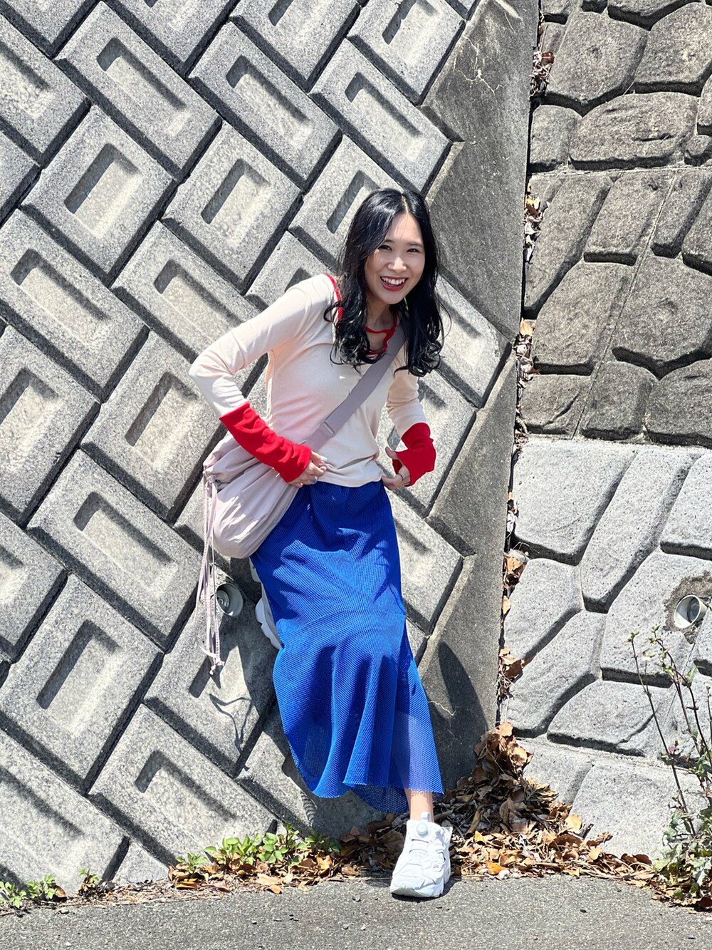 レッド系のTシャツ/カットソー、ブルー系のスカート、グレー系のスニーカーを着用したレディースの春コーディネートの3枚目の写真