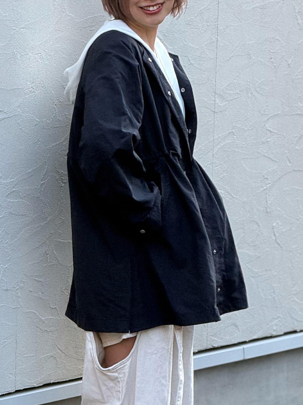 ブルー系のノーカラーコート、ホワイト系のデニムパンツ、ブルー系のスニーカーを着用したレディースの冬コーディネートの2枚目の写真