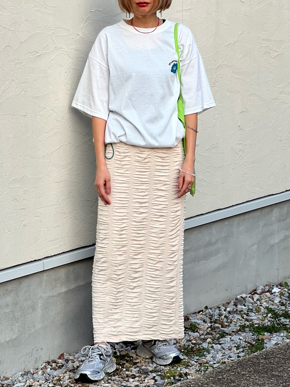 ホワイト系のTシャツ/カットソー、ホワイト系のスカート、シルバー系のスニーカーを着用したレディースの春コーディネートの3枚目の写真