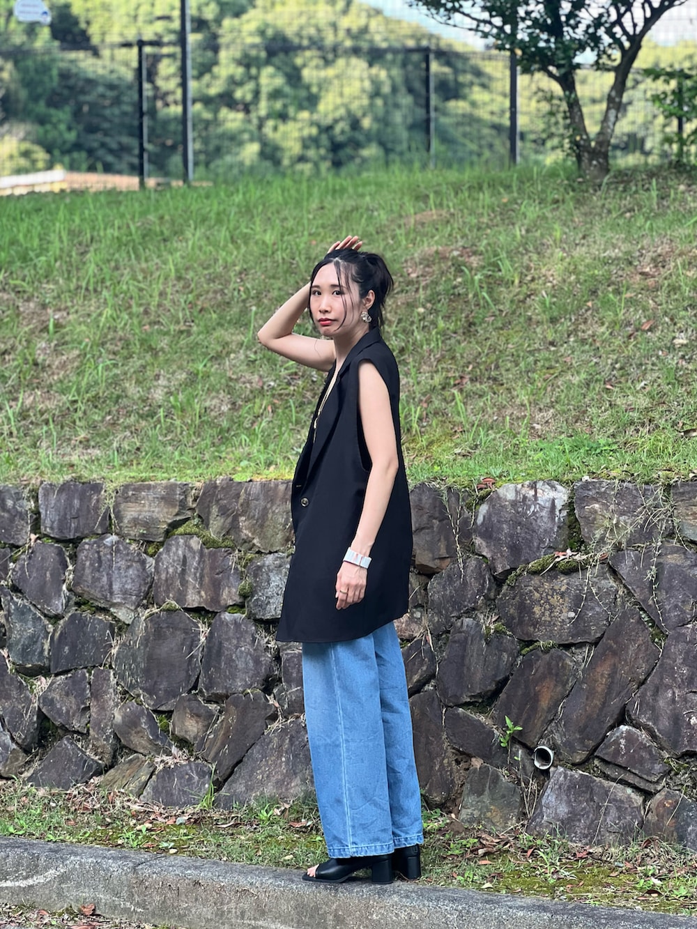 ブルー系のデニムパンツ、ブラウン系のショルダーバッグ、ブラック系のブーツを着用したレディースの夏コーディネートの5枚目の写真