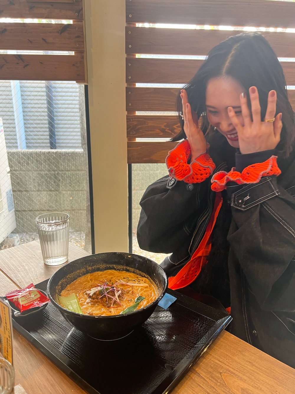 ブラック系のモッズコート、オレンジ系のカーディガン/ボレロ、ブラック系のワンピースを着用したレディースの冬コーディネートの4枚目の写真