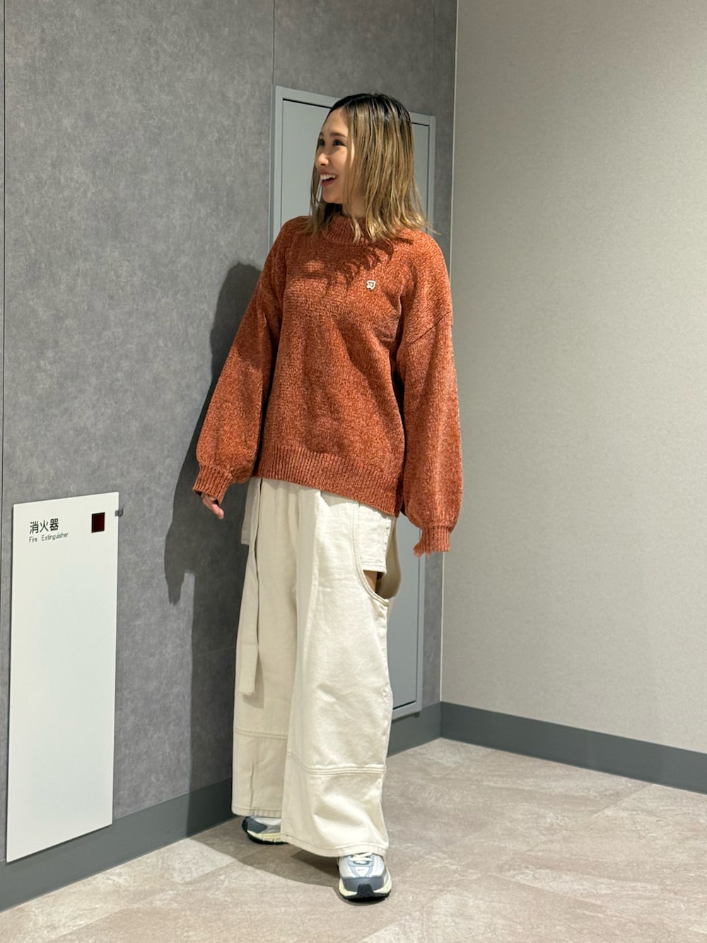 ブラウン系のニット/セーター、ホワイト系のデニムパンツ、グレー系のスニーカーを着用したレディースの秋コーディネートの4枚目の写真