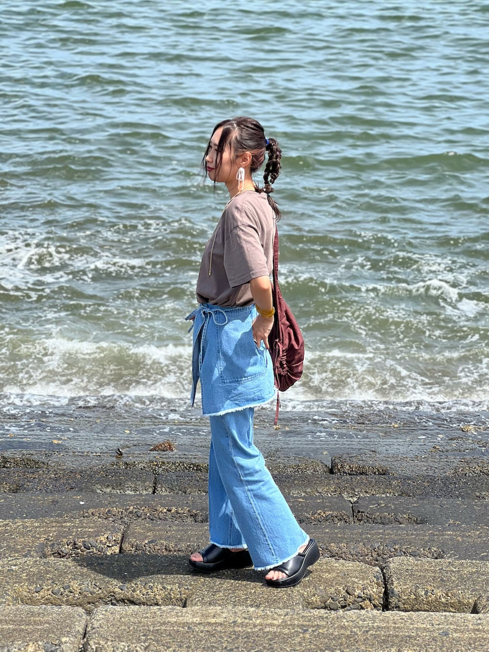 ブルー系のデニムパンツ、ブラウン系のTシャツ/カットソー、ブラック系のサンダルを着用したレディースの夏コーディネートの3枚目の写真