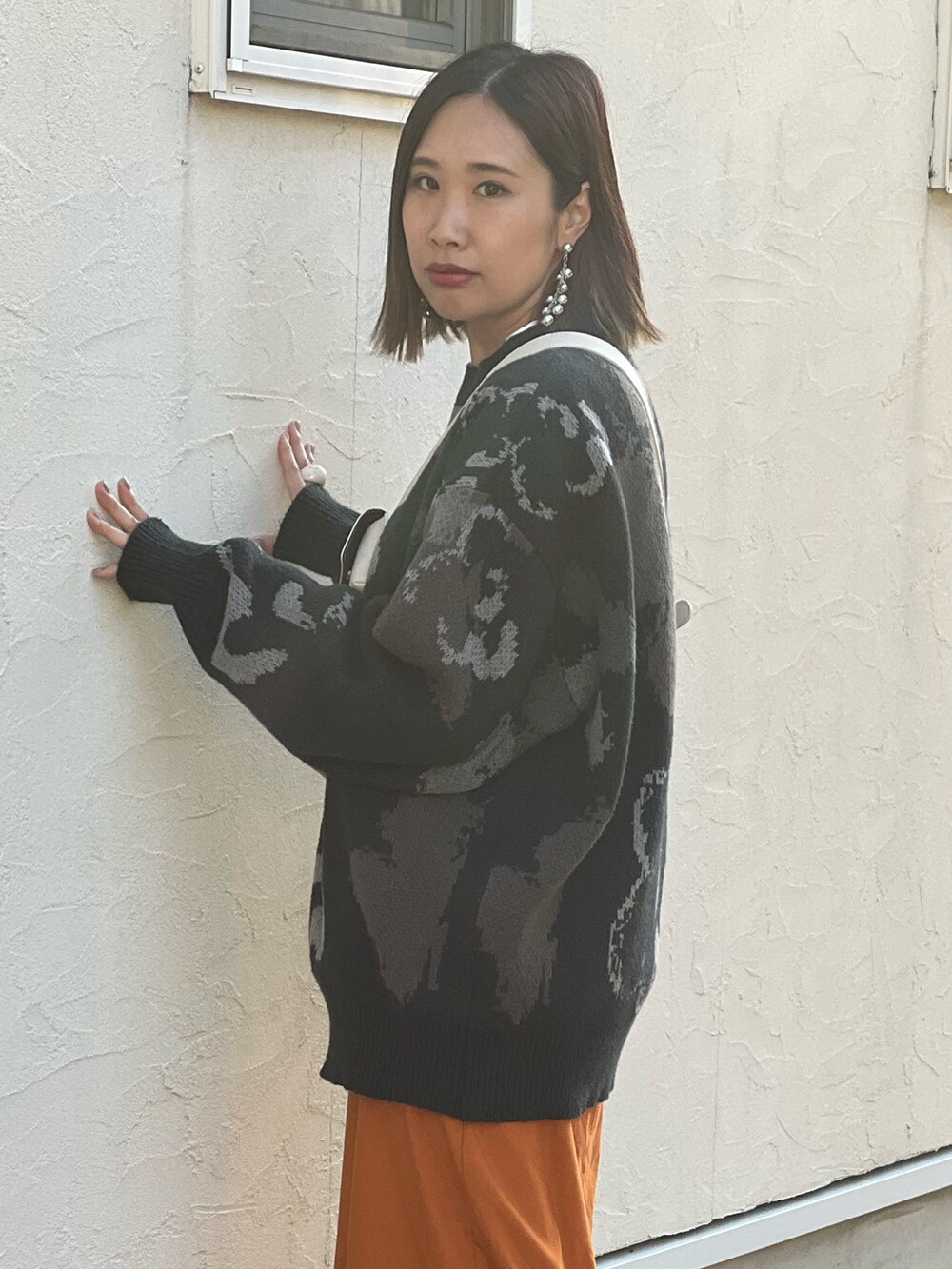 ブラック系のニット/セーター、イエロー系のスカート、ブラック系のブーツを着用したレディースの秋コーディネートの2枚目の写真