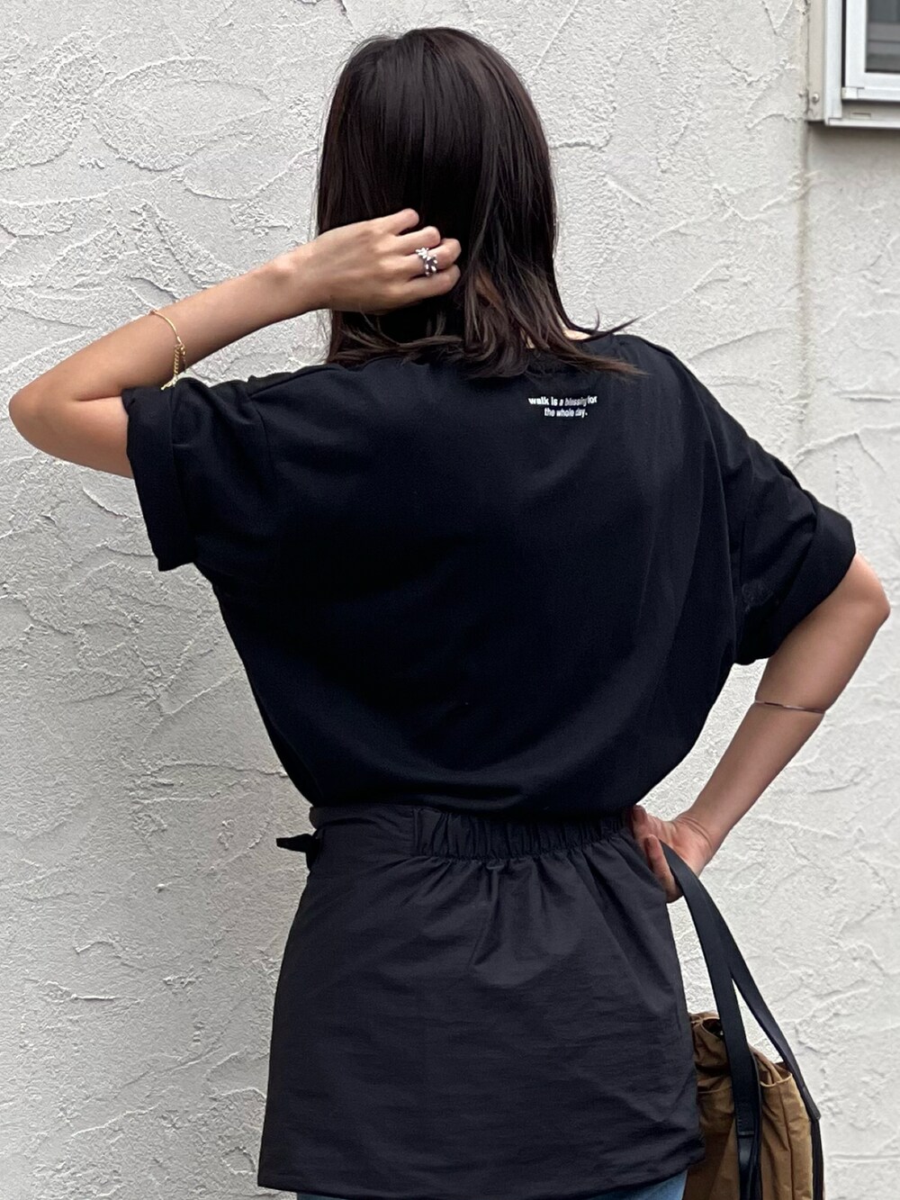 ブラック系のTシャツ/カットソー、ブルー系のデニムパンツ、ベージュ系のトートバッグを着用したレディースの春コーディネートの4枚目の写真