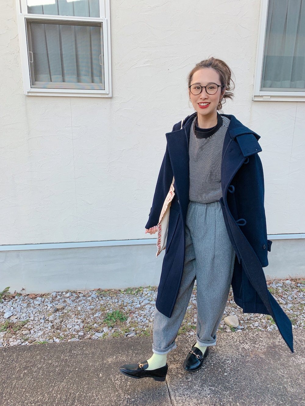 ブラック系のダッフルコート、ブラック系のローファー、レッド系のトートバッグを着用したレディースの冬コーディネートの2枚目の写真