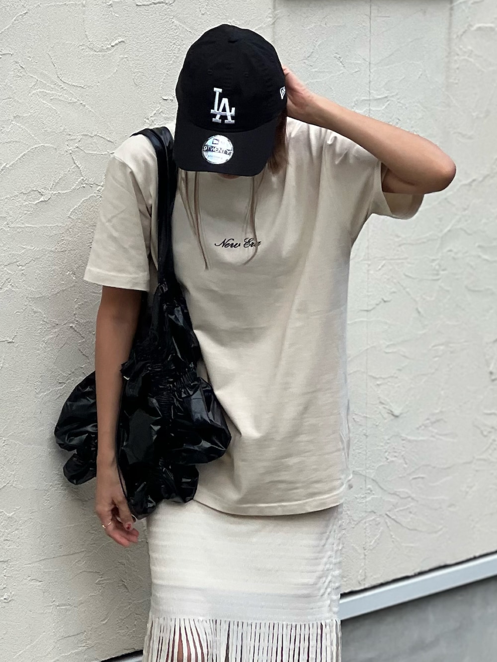 ベージュ系のTシャツ/カットソー、ブラック系のトートバッグ、ホワイト系のスカートを着用したレディースの夏コーディネートの3枚目の写真