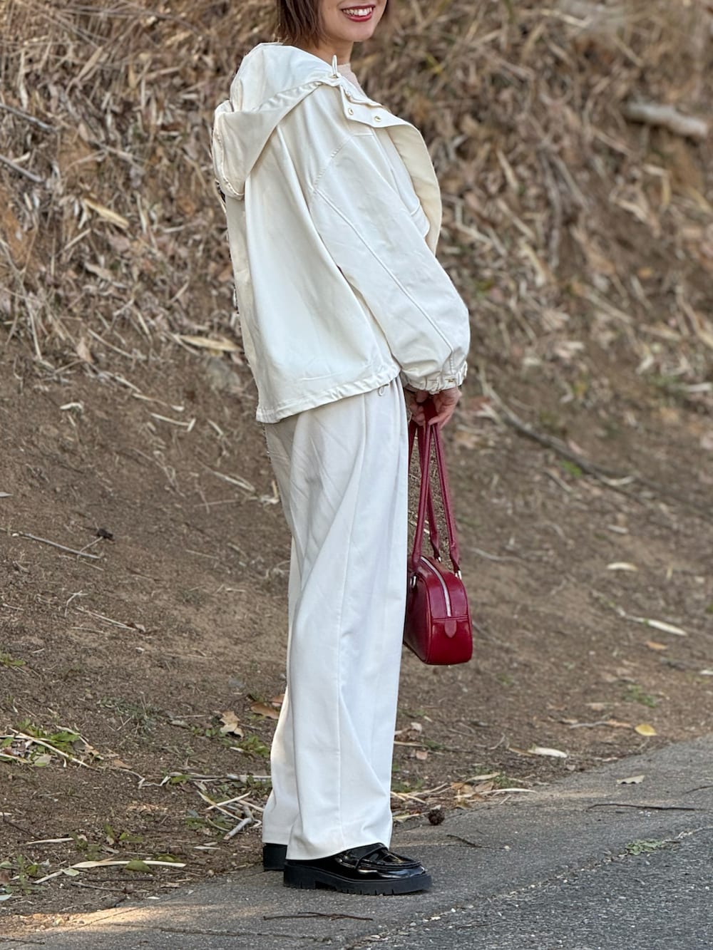 ホワイト系のマウンテンパーカー、ベージュ系のニット/セーター、レッド系のボストンバッグを着用したレディースの春コーディネートの3枚目の写真