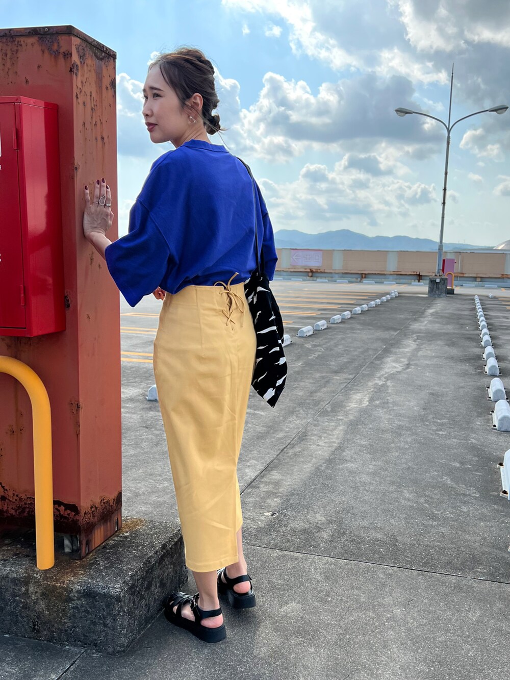 ブルー系のTシャツ/カットソー、イエロー系のスカート、ブラック系のサンダルを着用したレディースの夏コーディネートの2枚目の写真