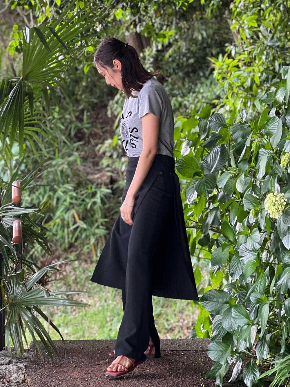 ブラック系のパンツ、ブラック系のバッグ、オレンジ系のサンダルを着用したレディースの春コーディネートの2枚目の写真