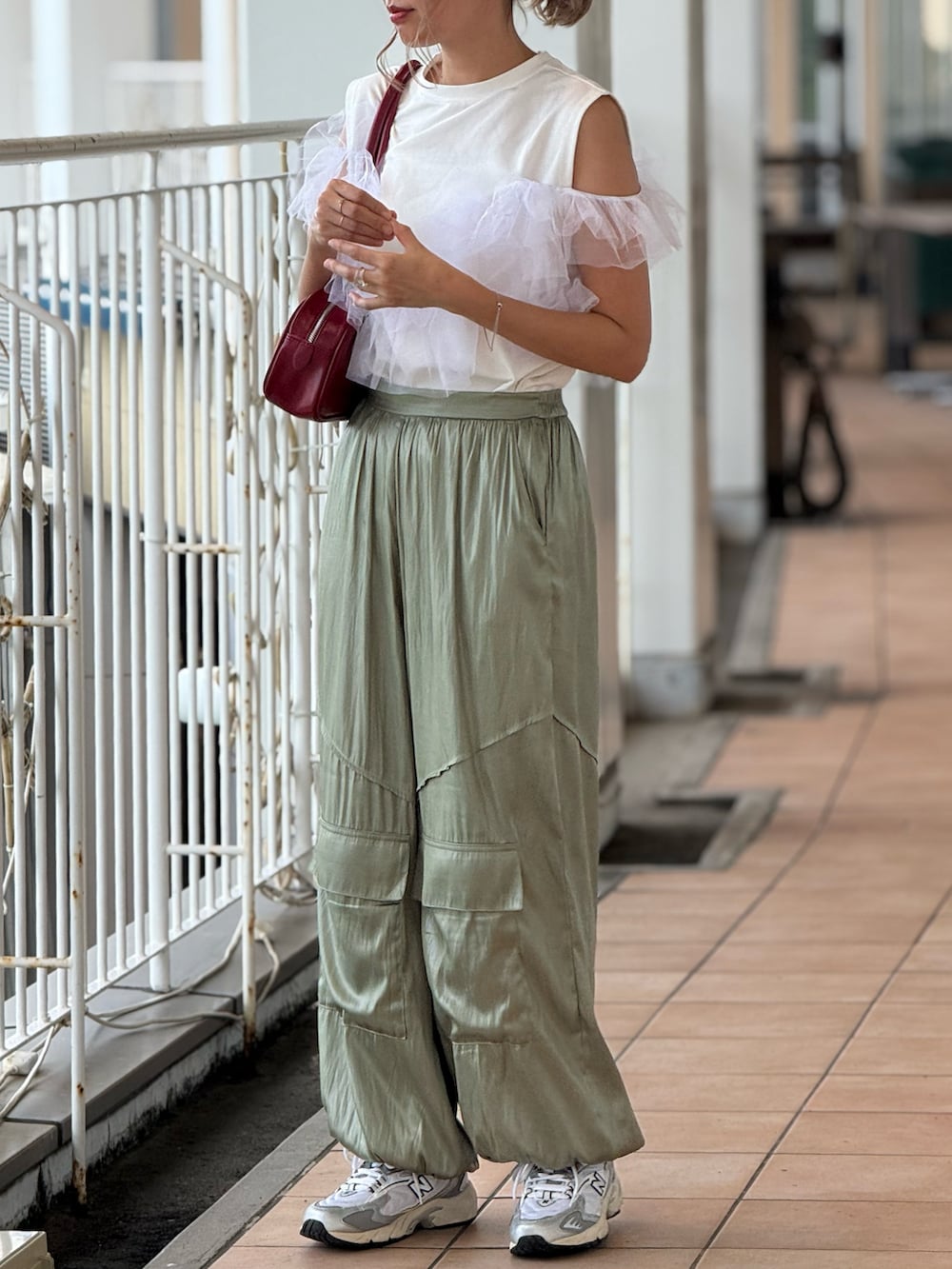 レッド系のボストンバッグ、シルバー系のスニーカー、ホワイト系のTシャツ/カットソーを着用したレディースの秋コーディネートの2枚目の写真