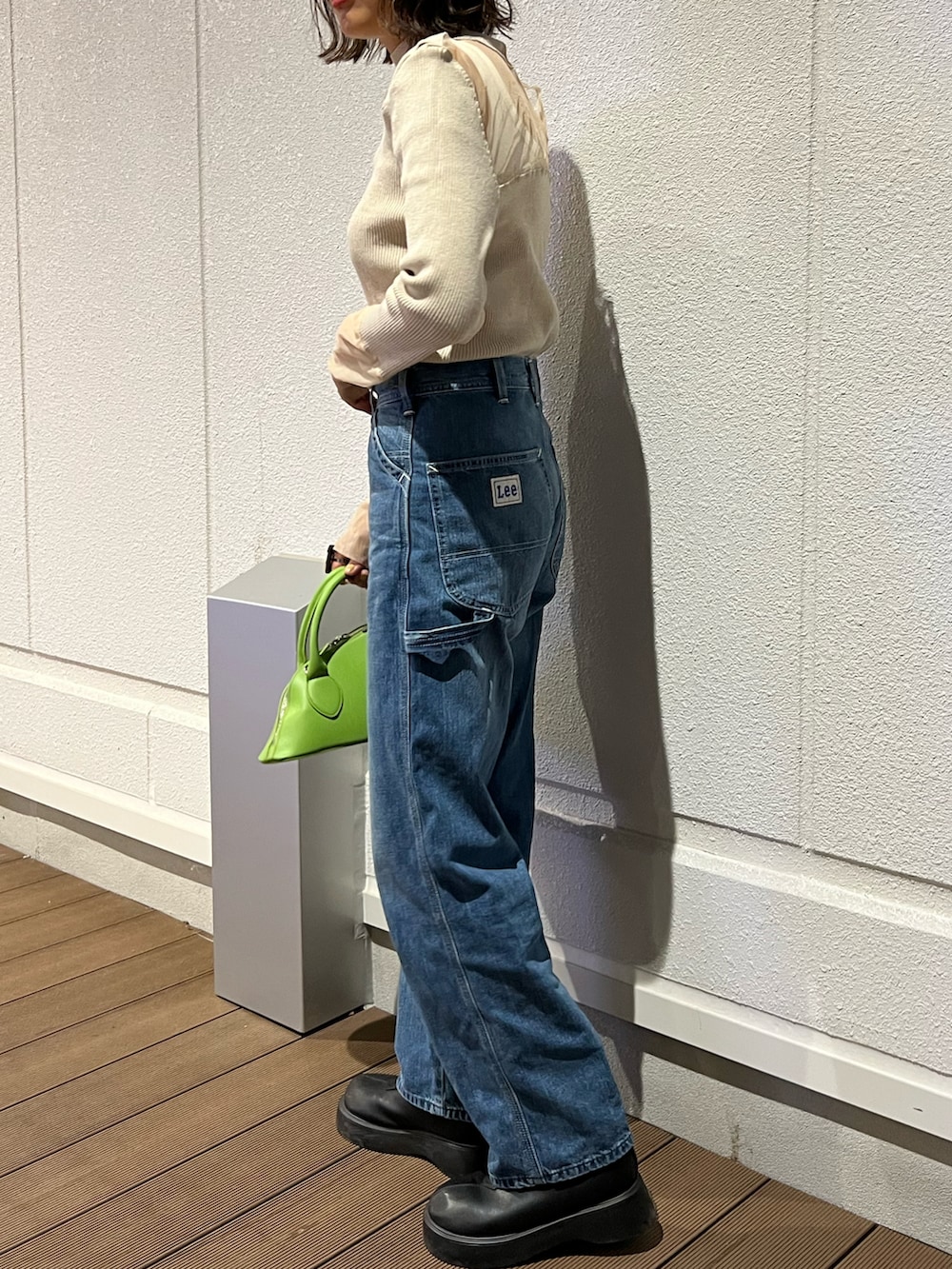 ブルー系のデニムパンツ、ホワイト系のタンクトップ、ベージュ系のニット/セーターを着用したレディースの秋コーディネートの4枚目の写真