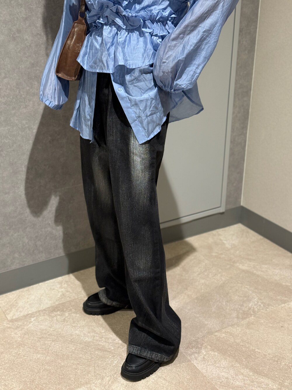 ブルー系のシャツ/ブラウス、ブラウン系のショルダーバッグ、ブラック系のデニムパンツを着用したレディースの秋コーディネートの2枚目の写真