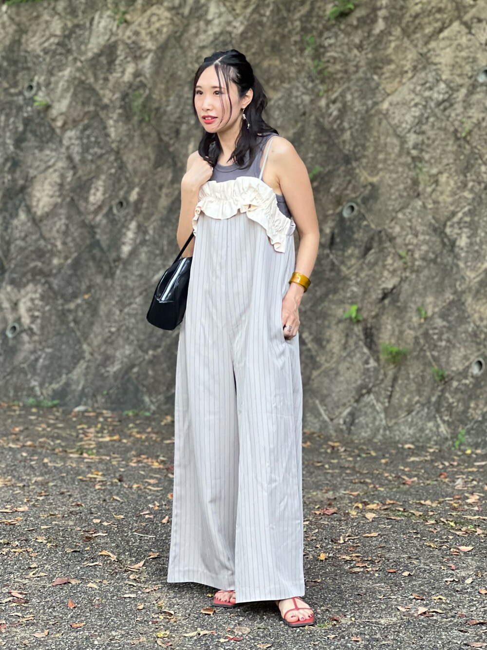 ベージュ系のサロペット/オーバーオール、ブラック系のボストンバッグ、オレンジ系のサンダルを着用したレディースの夏コーディネートの4枚目の写真