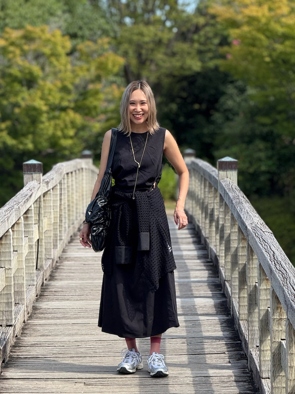 ブラック系のトートバッグ、シルバー系のスニーカー、ブラック系のワンピースを着用したレディースの秋コーディネートの2枚目の写真