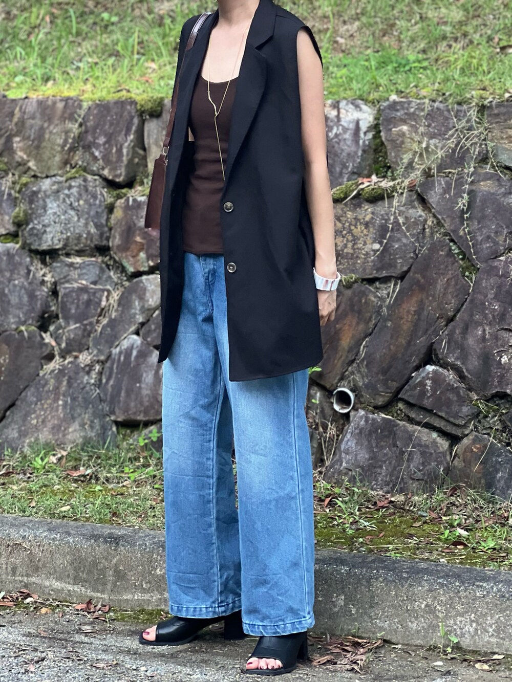 ブルー系のデニムパンツ、ブラウン系のショルダーバッグ、ブラック系のブーツを着用したレディースの夏コーディネートの4枚目の写真