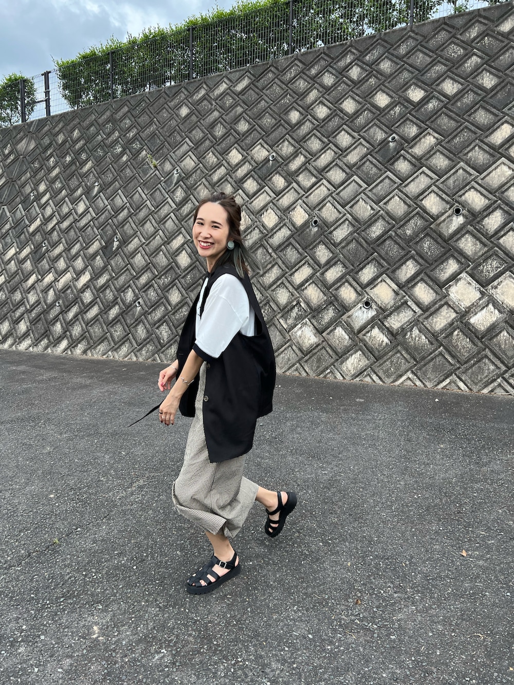 ブラック系のTシャツ/カットソー、ベージュ系のスカート、ブラック系のサンダルを着用したレディースの夏コーディネートの2枚目の写真