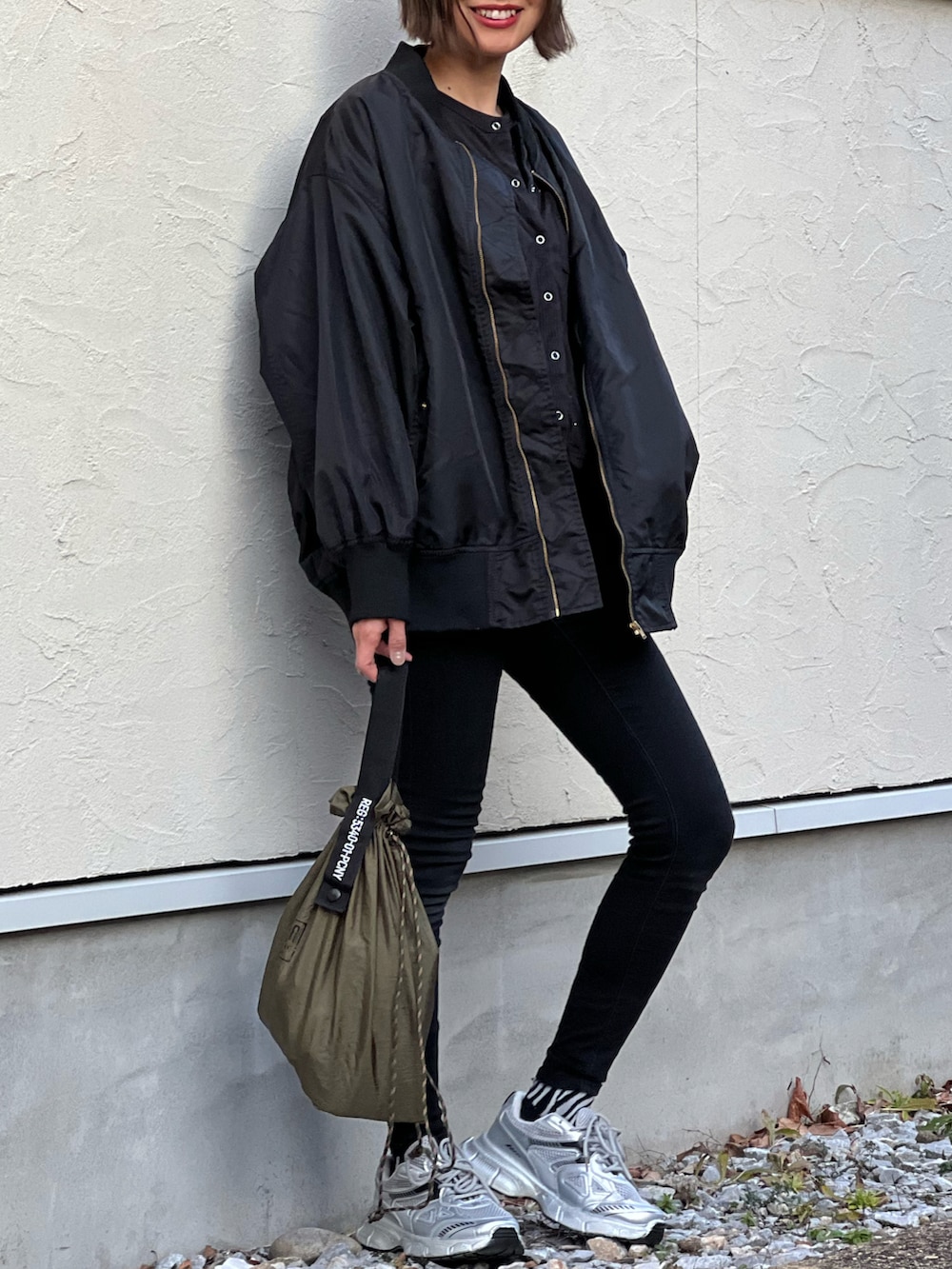 ブラック系のブルゾン、ブラック系のカーディガン/ボレロ、シルバー系のスニーカーを着用したレディースの冬コーディネートの2枚目の写真