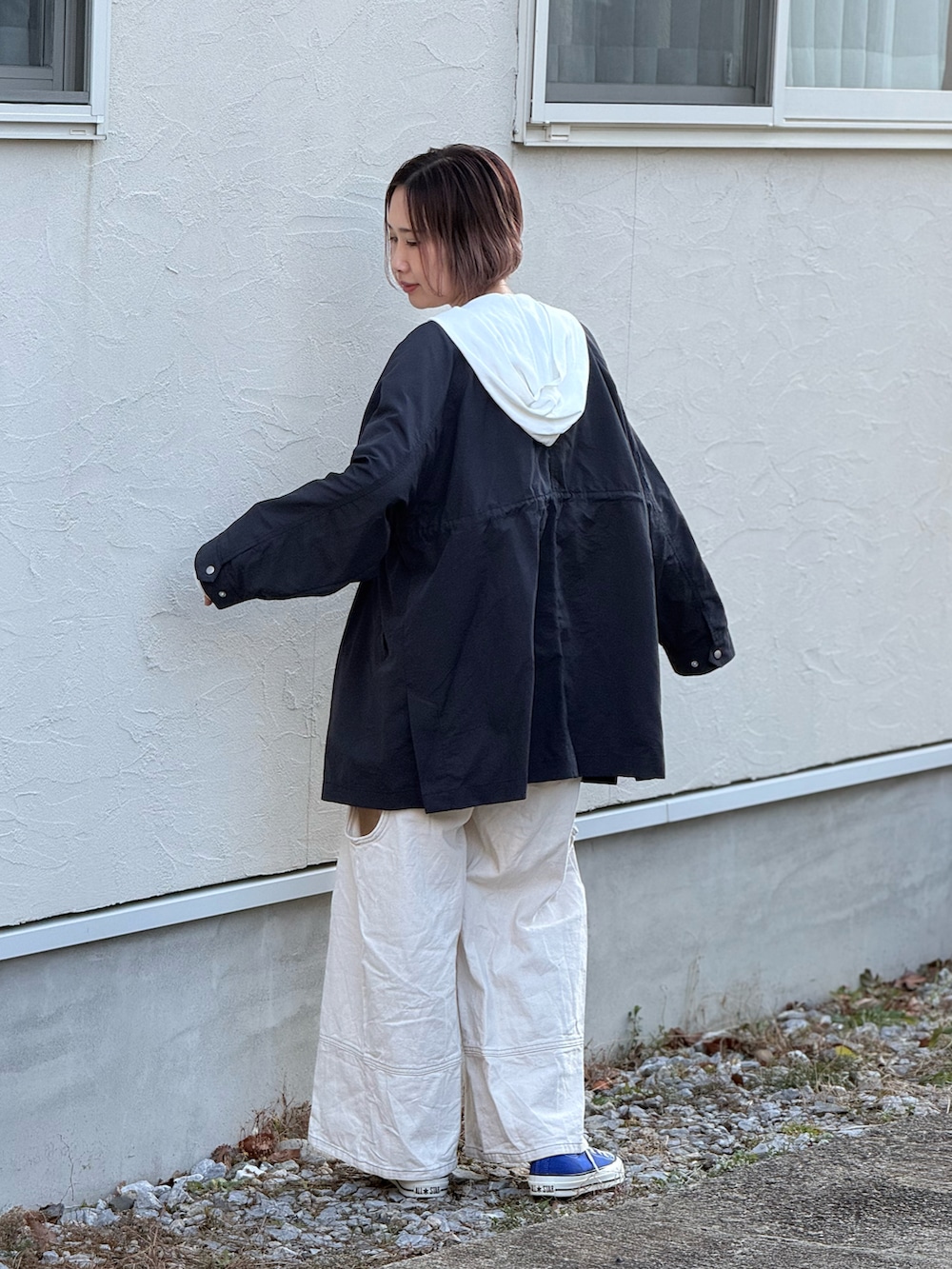 ブルー系のノーカラーコート、ホワイト系のデニムパンツ、ブルー系のスニーカーを着用したレディースの冬コーディネートの3枚目の写真