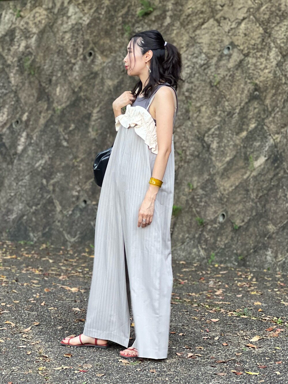 ベージュ系のサロペット/オーバーオール、ブラック系のボストンバッグ、オレンジ系のサンダルを着用したレディースの夏コーディネートの2枚目の写真