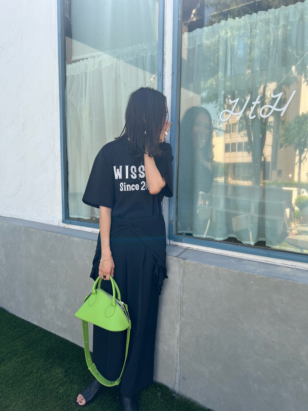 ブラック系のTシャツ/カットソー、ブラック系のブーツ、グリーン系のボストンバッグを着用したレディースの春コーディネートの2枚目の写真