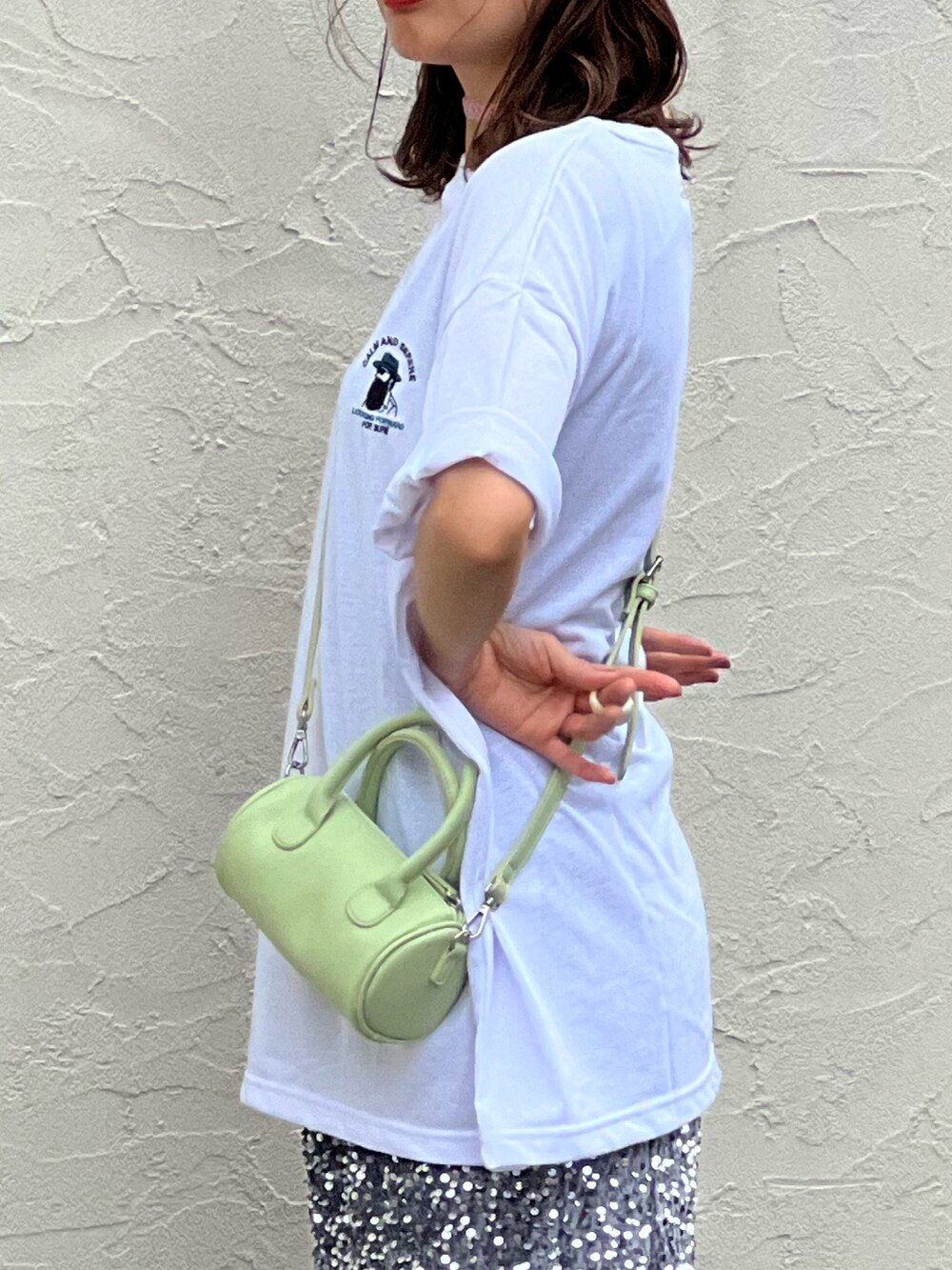ホワイト系のTシャツ/カットソー、シルバー系のスカート、グリーン系のショルダーバッグを着用したレディースの春コーディネートの2枚目の写真