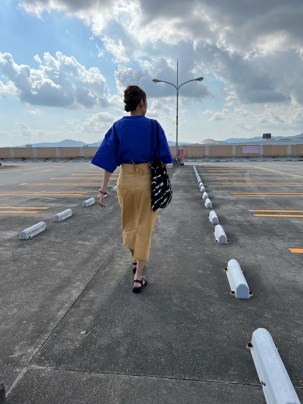 ブルー系のTシャツ/カットソー、イエロー系のスカート、ブラック系のサンダルを着用したレディースの夏コーディネートの4枚目の写真