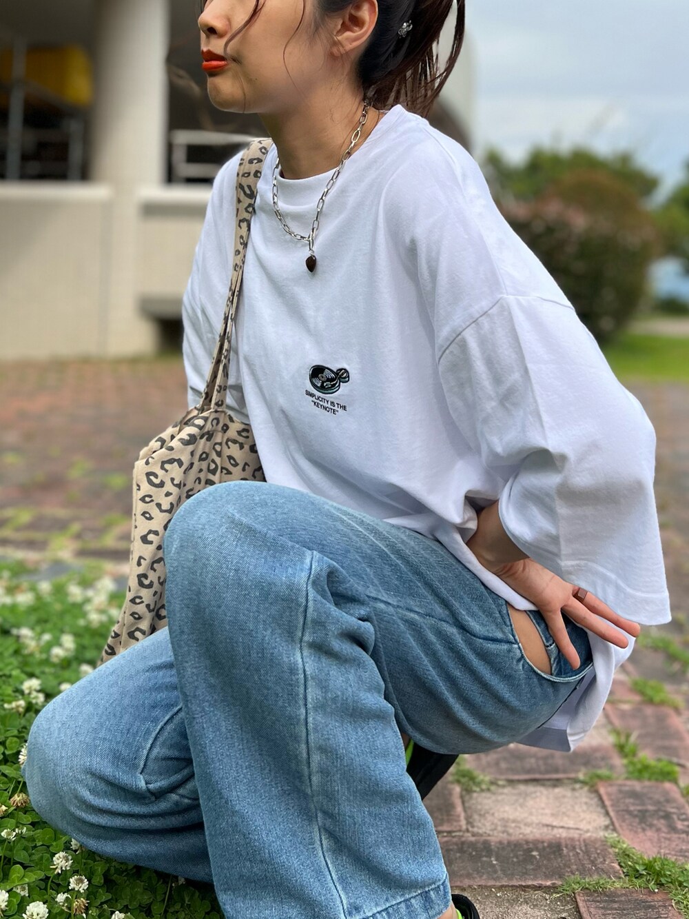 ホワイト系のTシャツ/カットソー、ブルー系のデニムパンツ、ブラック系のスニーカーを着用したレディースの夏コーディネートの3枚目の写真