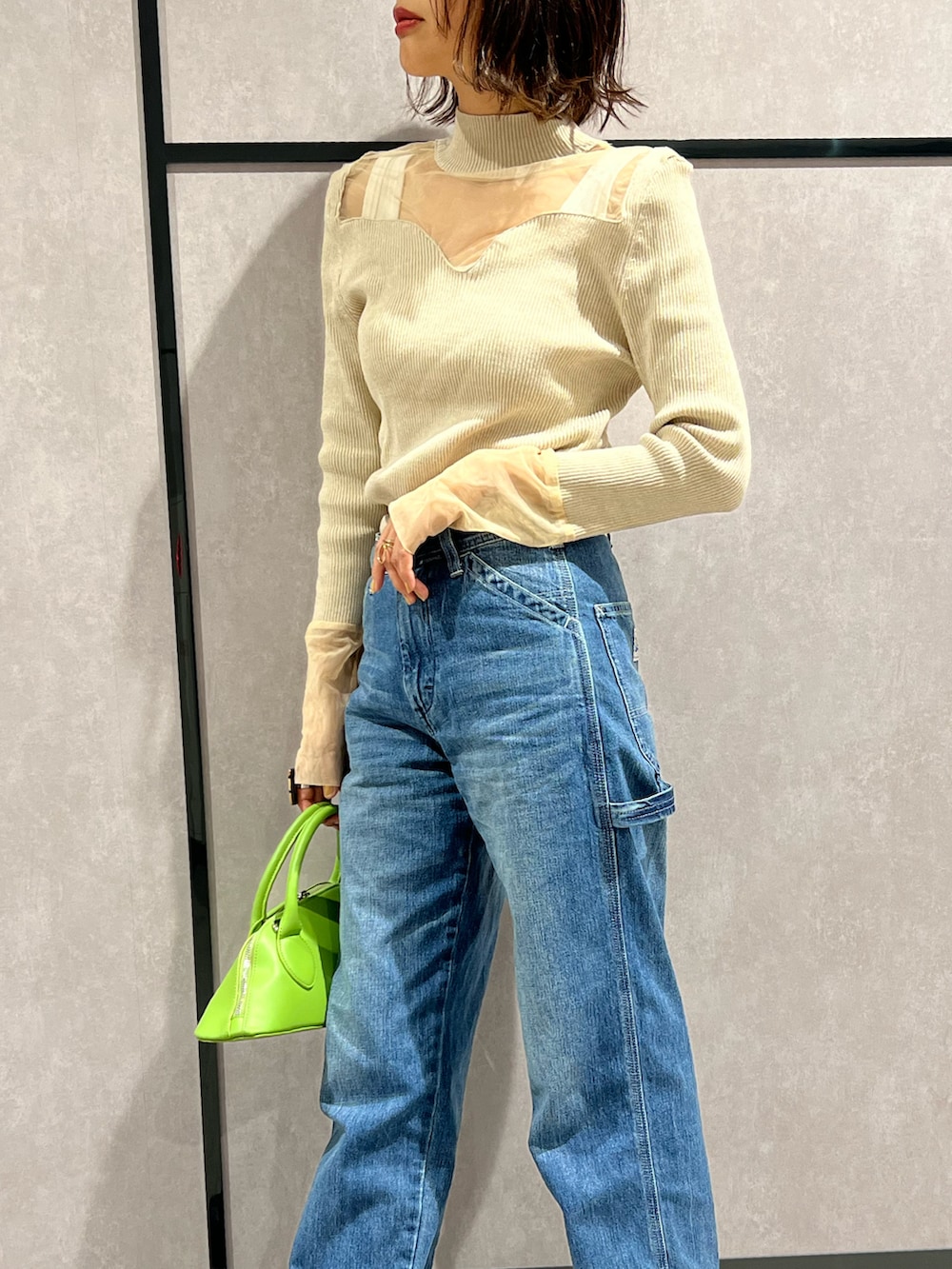 ブルー系のデニムパンツ、ホワイト系のタンクトップ、ベージュ系のニット/セーターを着用したレディースの秋コーディネートの2枚目の写真
