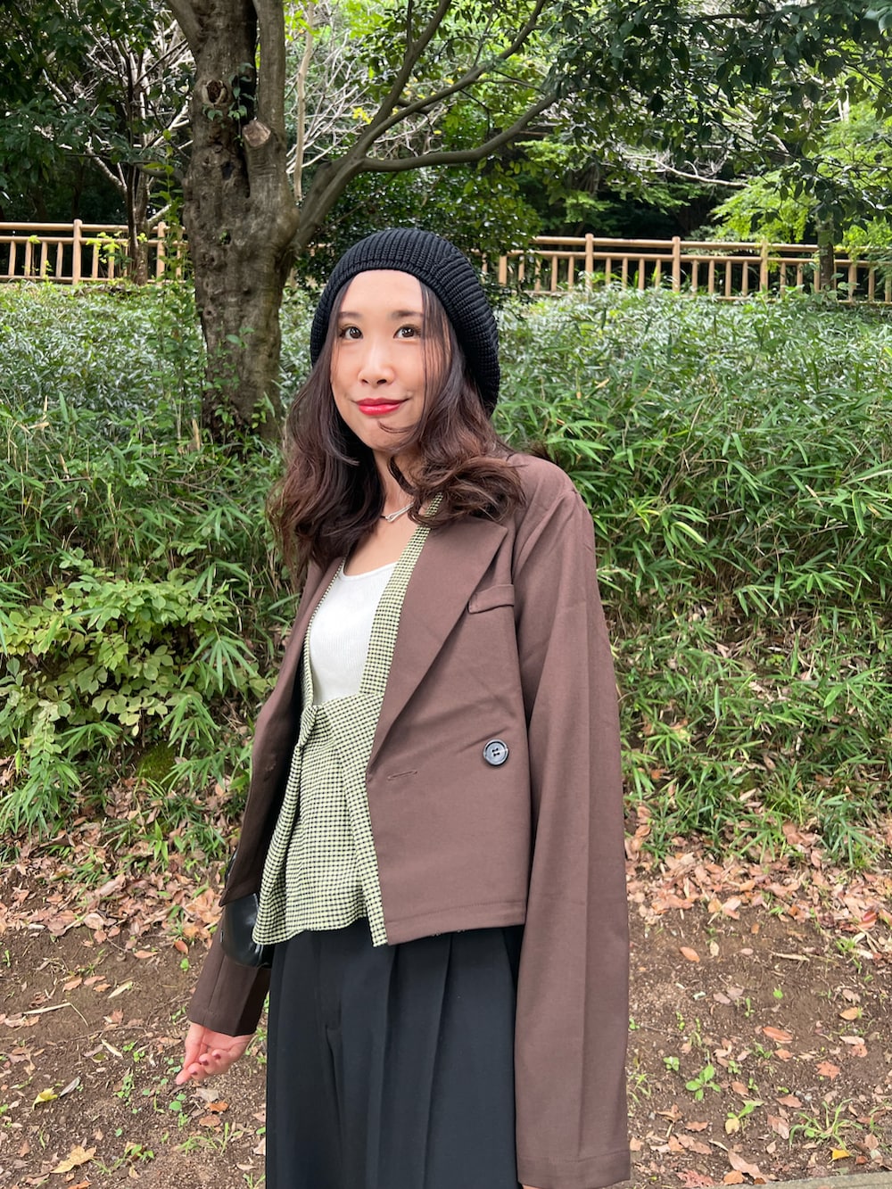 グリーン系のベスト、ブラウン系のジャケット/アウター、ブラック系のパンツを着用したレディースの秋コーディネートの2枚目の写真