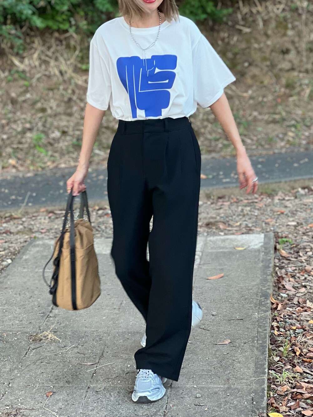 ホワイト系のTシャツ/カットソー、ベージュ系のトートバッグ、ブラック系のパンツを着用したレディースの秋コーディネートの3枚目の写真