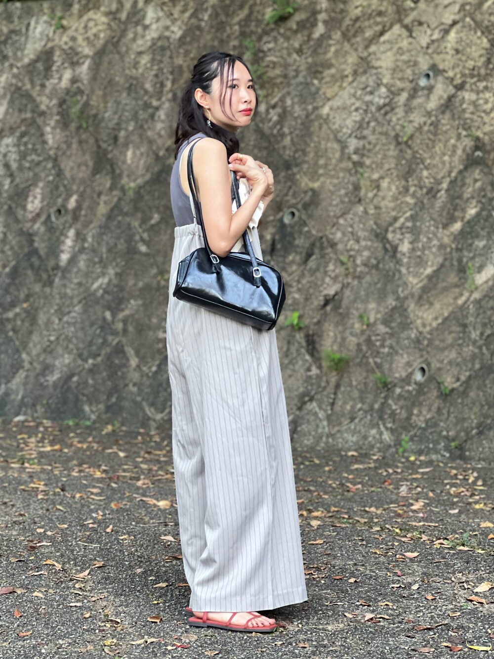 ベージュ系のサロペット/オーバーオール、ブラック系のボストンバッグ、オレンジ系のサンダルを着用したレディースの夏コーディネートの3枚目の写真