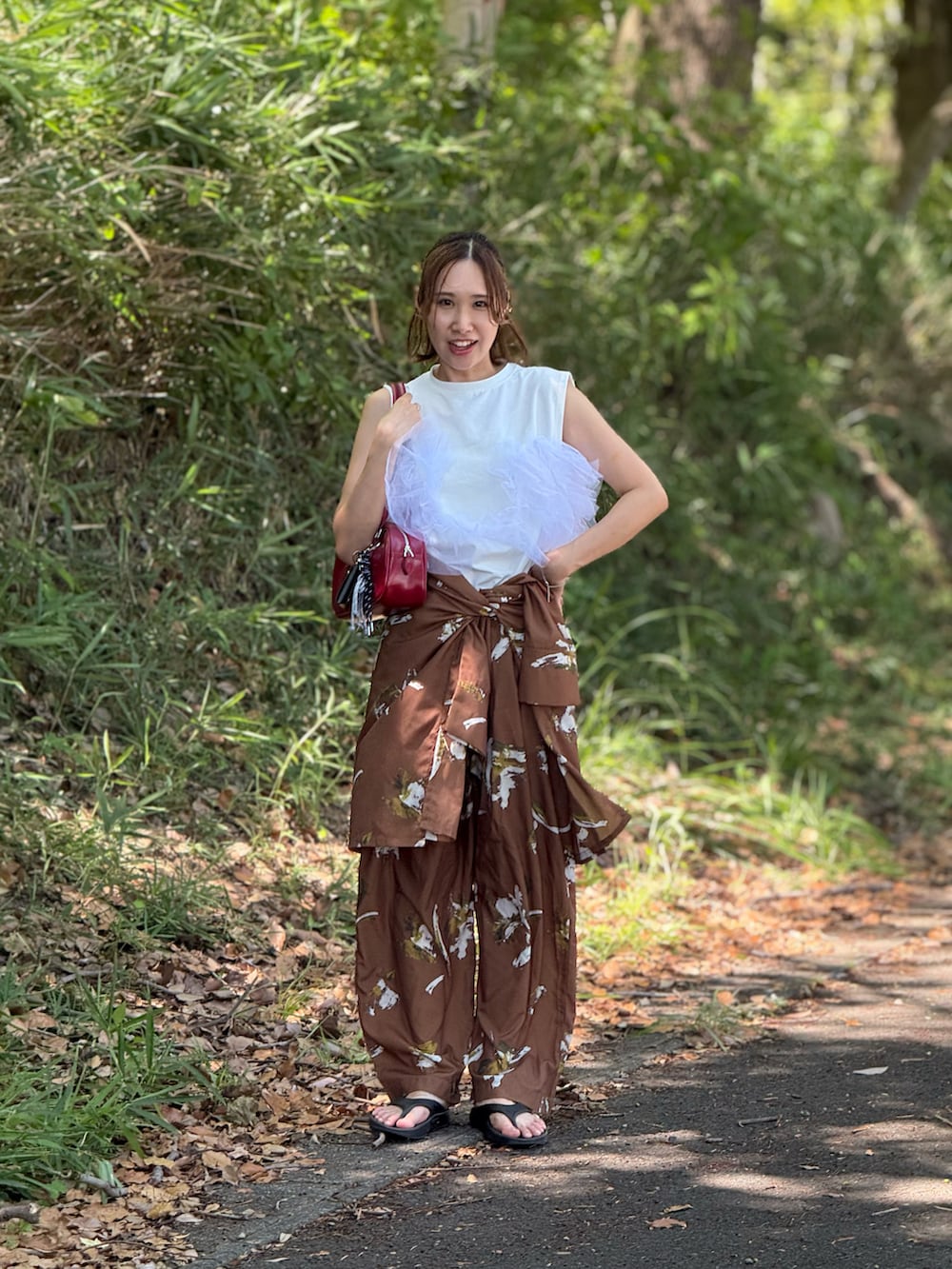 レッド系のボストンバッグ、グリーン系のその他パンツ、ホワイト系のTシャツ/カットソーを着用したレディースの秋コーディネートの3枚目の写真