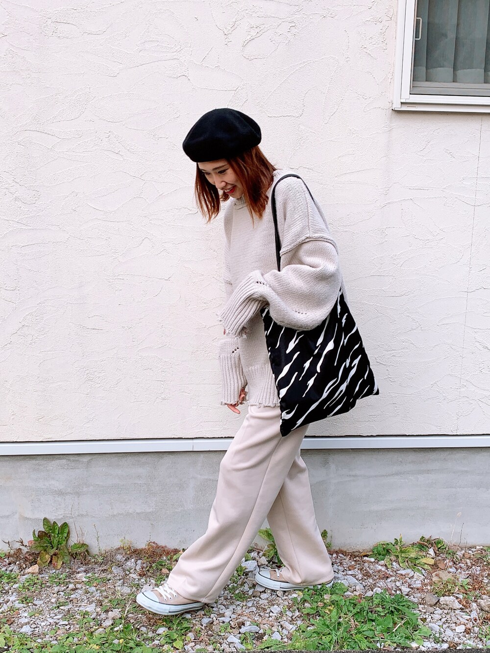 グレー系のニット/セーター、ホワイト系のスラックス、ベージュ系のスニーカーを着用したレディースの秋コーディネートの2枚目の写真