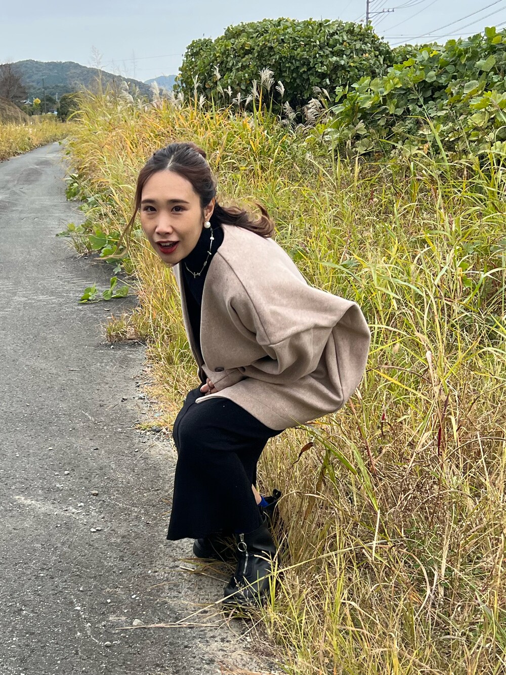 ピンク系のノーカラーコート、ブラック系のワンピース、ブラック系のブーツを着用したレディースの秋コーディネートの5枚目の写真