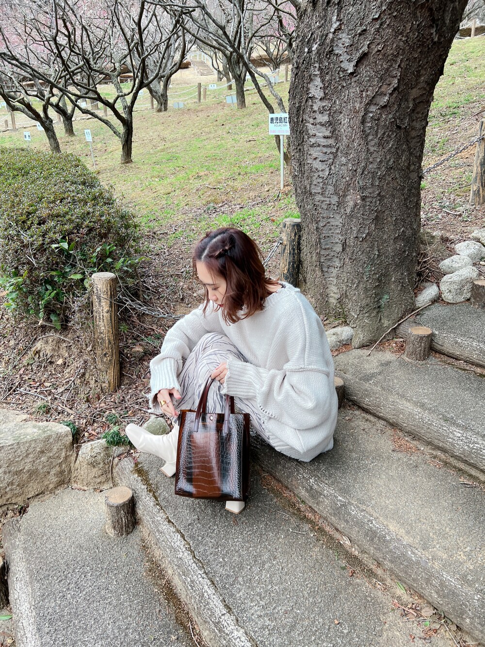 グレー系のニット/セーター、ホワイト系のブーツ、ブラウン系のトートバッグを着用したレディースの春コーディネートの2枚目の写真