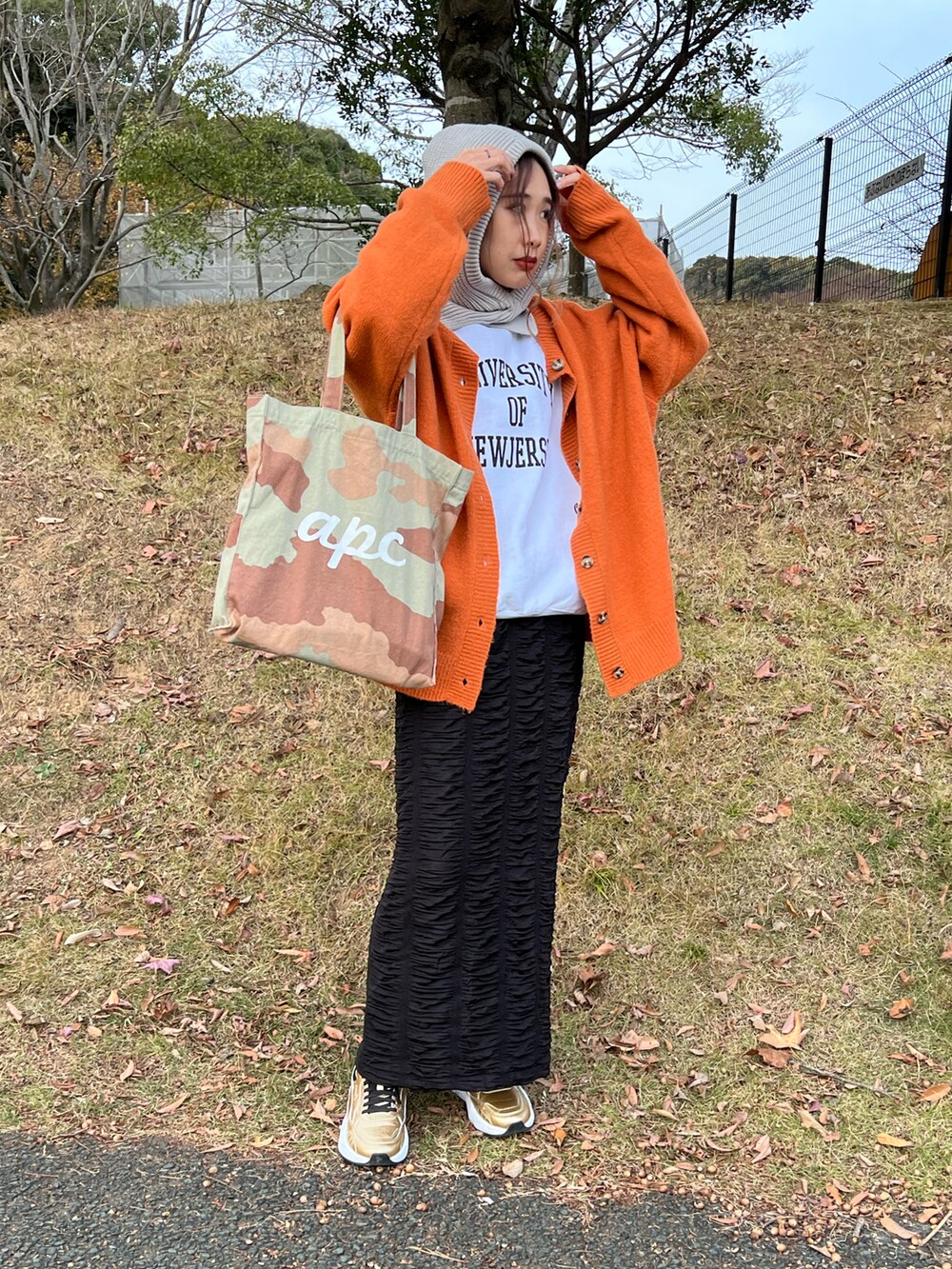 ホワイト系のスウェット、オレンジ系のカーディガン/ボレロ、ブラック系のスカートを着用したレディースの冬コーディネートの3枚目の写真