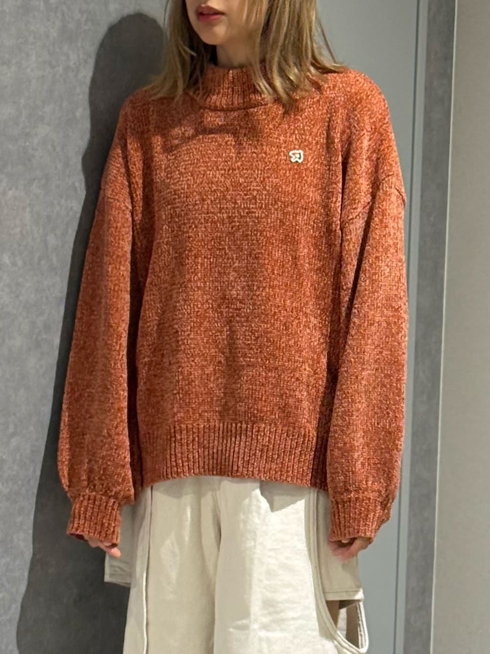 ブラウン系のニット/セーター、ホワイト系のデニムパンツ、グレー系のスニーカーを着用したレディースの秋コーディネートの2枚目の写真