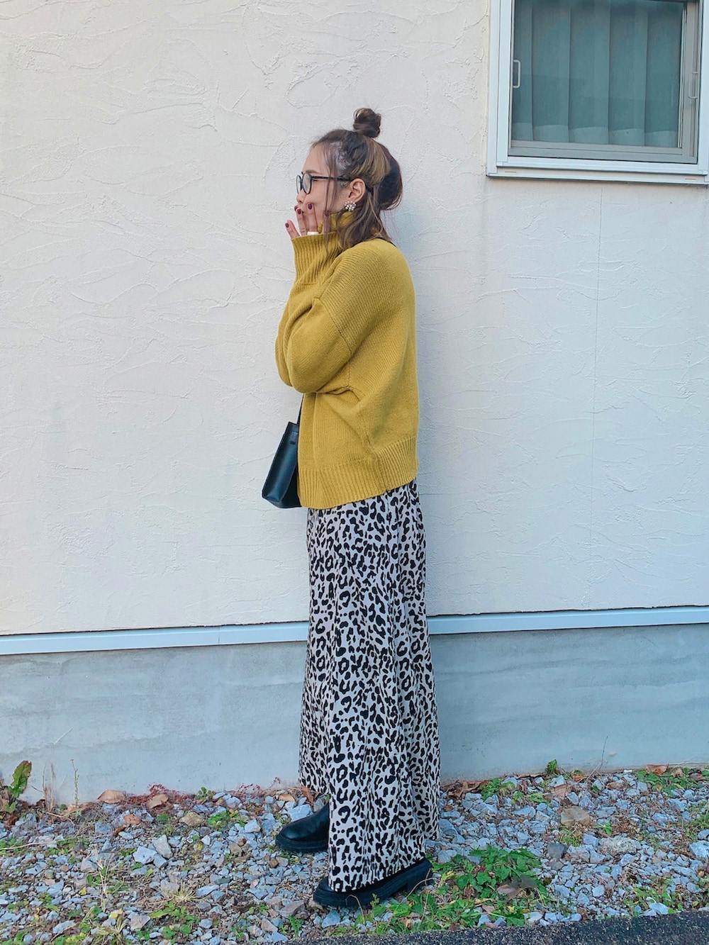 イエロー系のニット/セーター、ベージュ系のスカート、ブラック系のトートバッグを着用したレディースの冬コーディネートの2枚目の写真