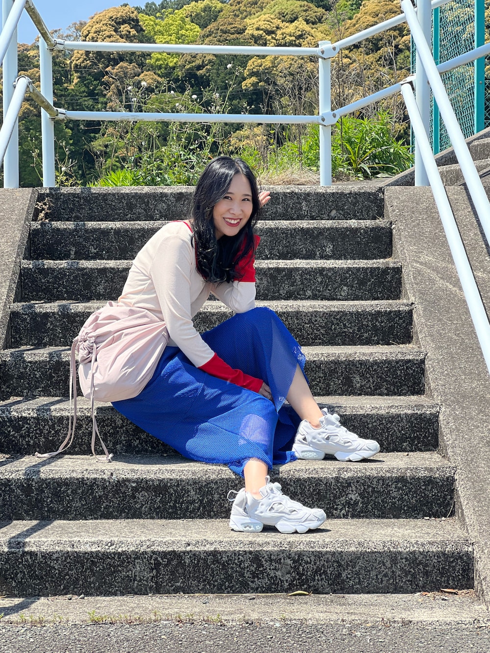 レッド系のTシャツ/カットソー、ブルー系のスカート、グレー系のスニーカーを着用したレディースの春コーディネートの5枚目の写真