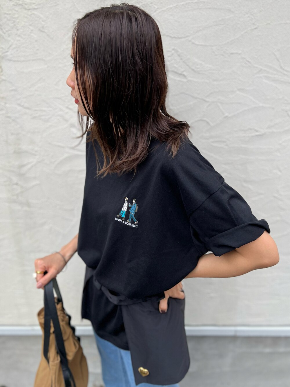 ブラック系のTシャツ/カットソー、ブルー系のデニムパンツ、ベージュ系のトートバッグを着用したレディースの春コーディネートの2枚目の写真