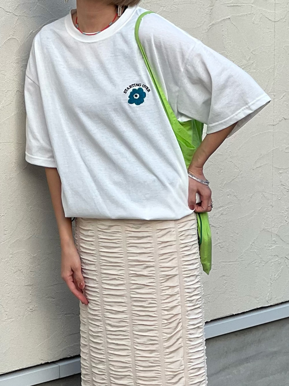 ホワイト系のTシャツ/カットソー、ホワイト系のスカート、シルバー系のスニーカーを着用したレディースの春コーディネートの2枚目の写真